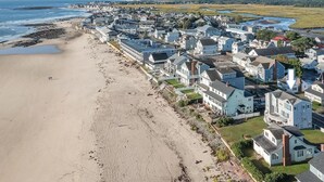 Une zone résidentielle côtière avec des maisons le long de la plage, un ciel dégagé et une mer calme.