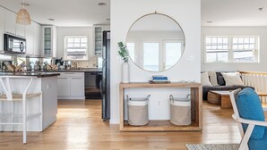 Une cuisine moderne avec des meubles blancs, un îlot central et un coin repas comprenant une table et des chaises en bois.