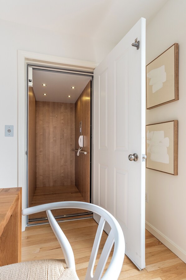 Una habitación con piso de madera, una puerta blanca y una silla blanca.