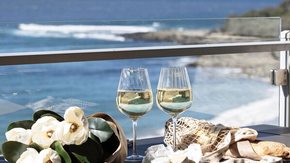 Two glasses of white wine on a table with a view of the ocean.