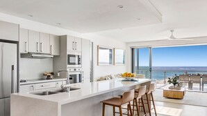 A modern kitchen with a large island, stainless steel appliances, and a view of the ocean. - White Sails 3 - Oceanfront Luxury, Pool & Convent Beach Views - Holiday Yamba (Yamba)