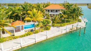 Une propriété située au bord de l’eau, comprenant une grande maison, une piscine et un quai s’avançant dans l’eau.