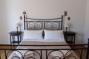 A bed with a black metal frame, two nightstands with lamps, and decorative masks on the wall. - Casa Monte Mulini (Rovinj)