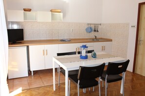 A compact kitchen with a white countertop, a sink, and a dining area with a table and chairs. - Casa Monte Mulini (Rovinj)