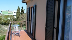 A balcony with a table and chairs, a sliding door, and a view of the surrounding area. - Casa Monte Mulini (Rovinj)