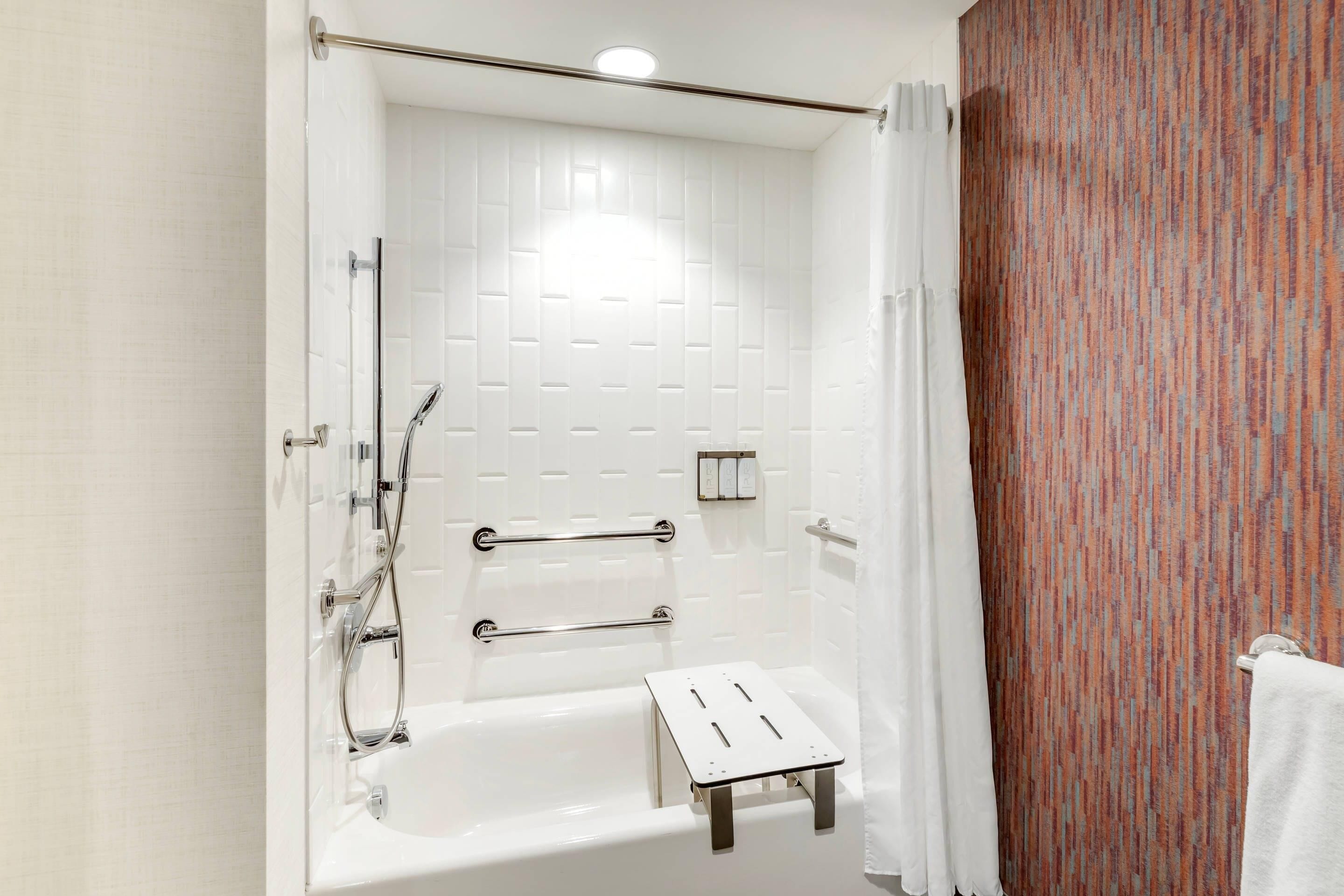 A modern bathroom with a white bathtub, a shower area, and a towel rack.