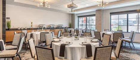 A conference room with round tables, chairs, and a buffet area.