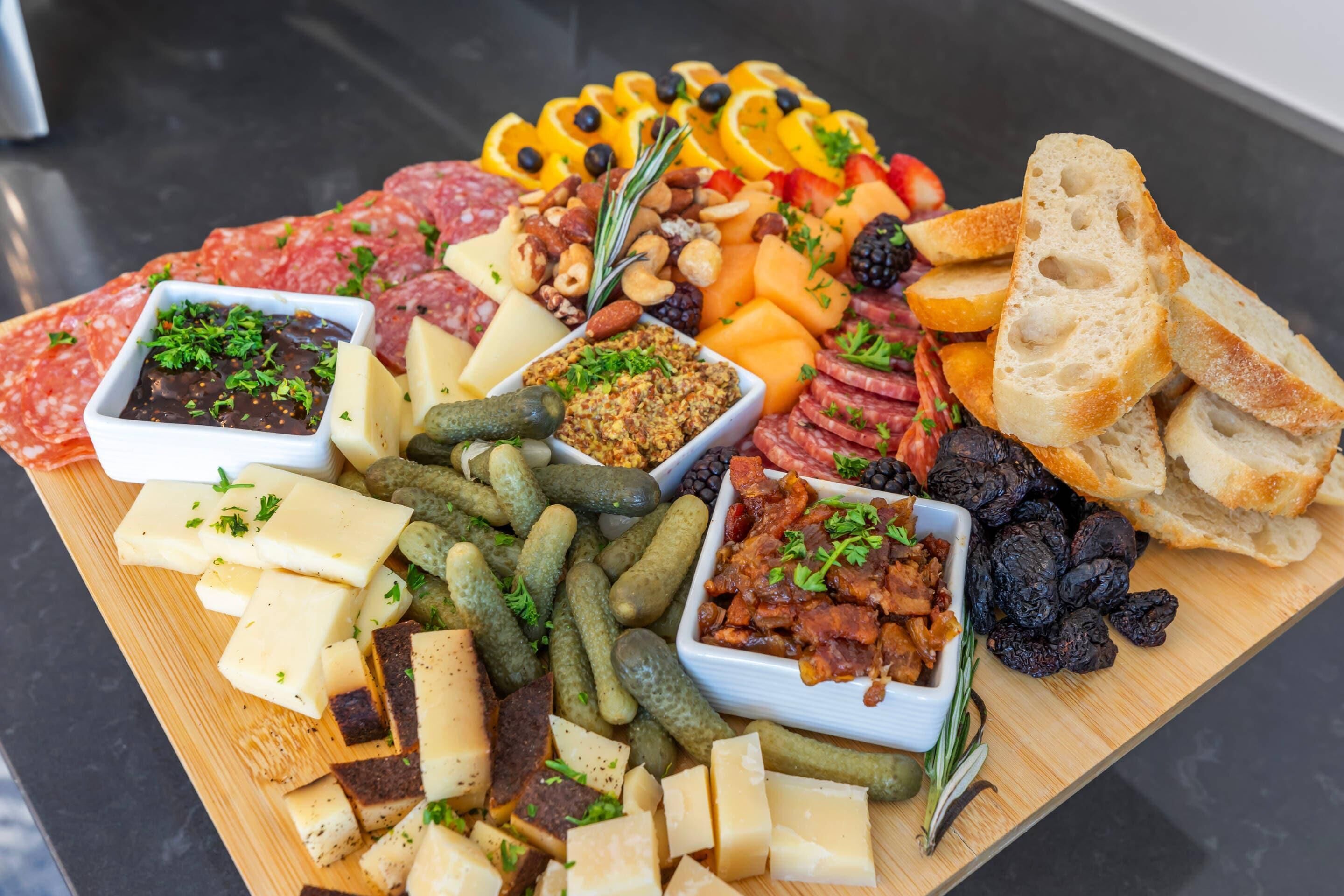 A charcuterie board with various cheeses, meats, fruits, and bread.