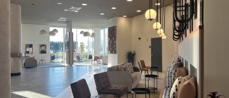 A spacious lobby with a seating area, a reception desk, and a large window providing a view of the outdoors.