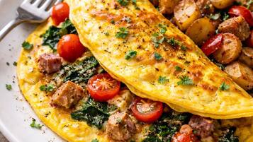 A plate of food with an omelette and roasted potatoes.