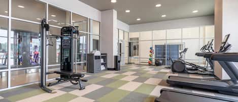A gym with treadmills, a weight machine, and a mirrored wall.