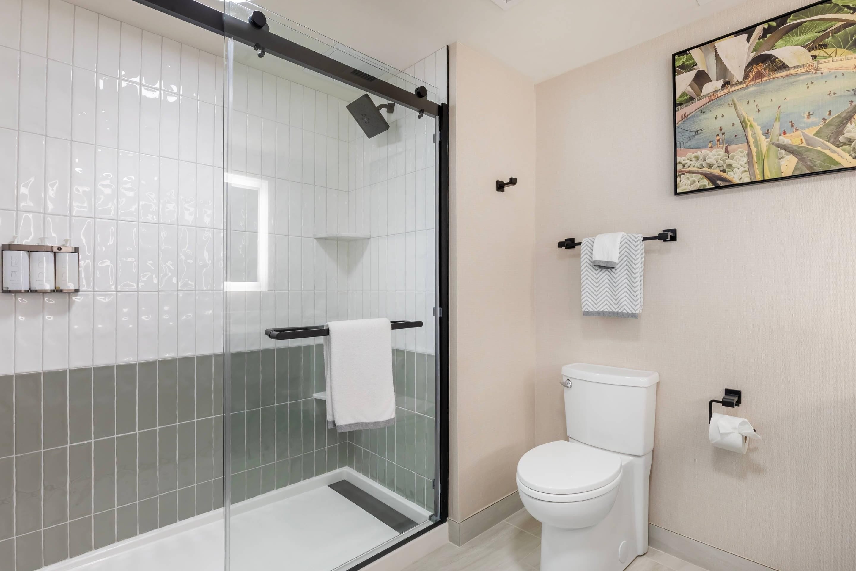 A modern bathroom with a glass-enclosed shower, a toilet, and a wall-mounted towel rack.
