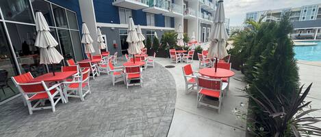 Terraza en la azotea con mobiliario exterior y sombrillas, con vistas a una piscina.