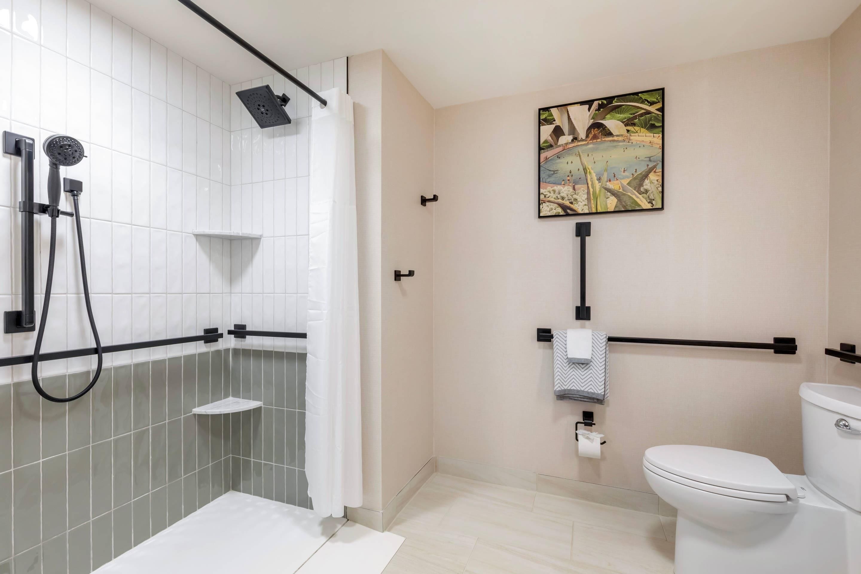 A modern bathroom with a shower, toilet, and a painting on the wall.