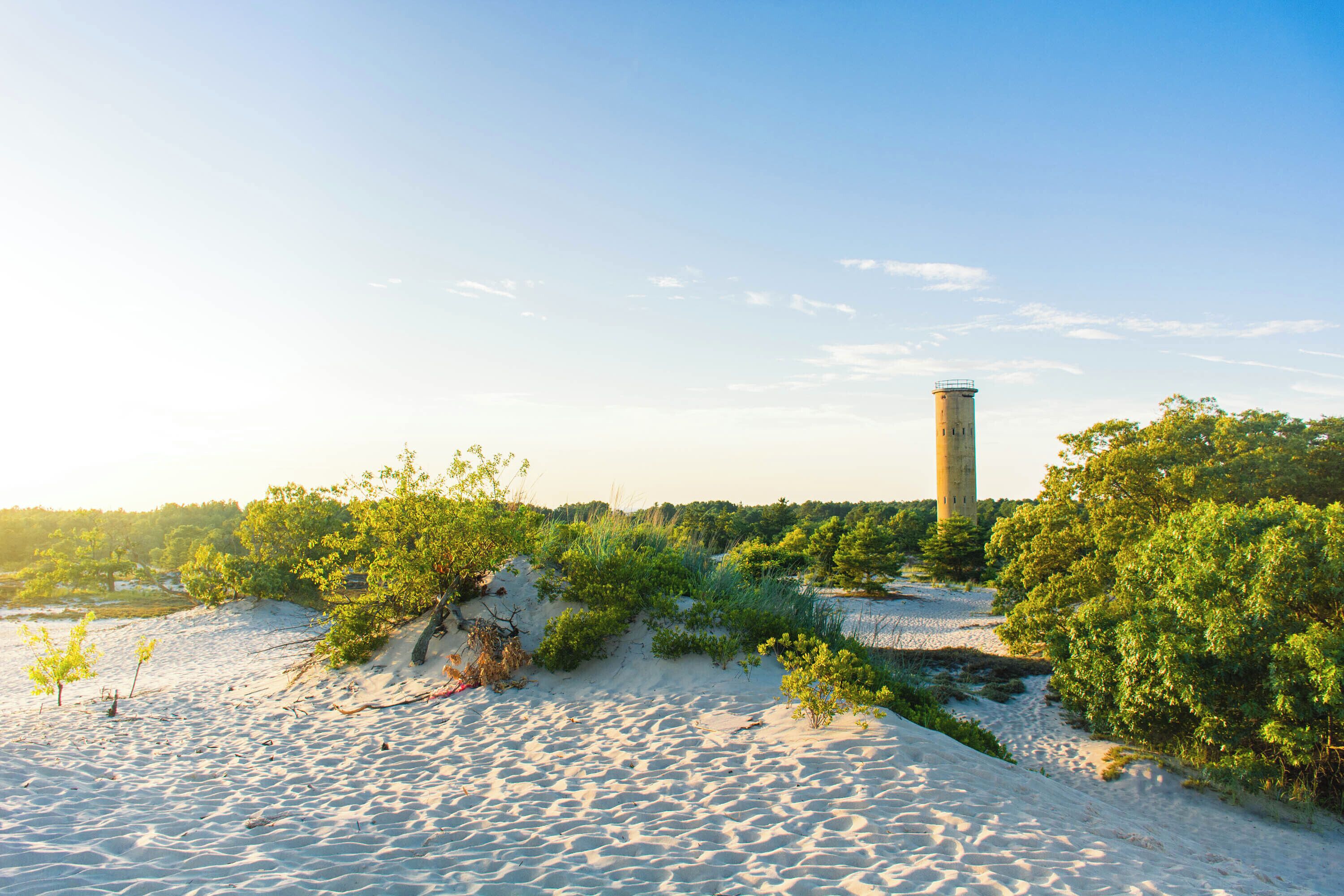 A sandy beach with a tower structure in the background.