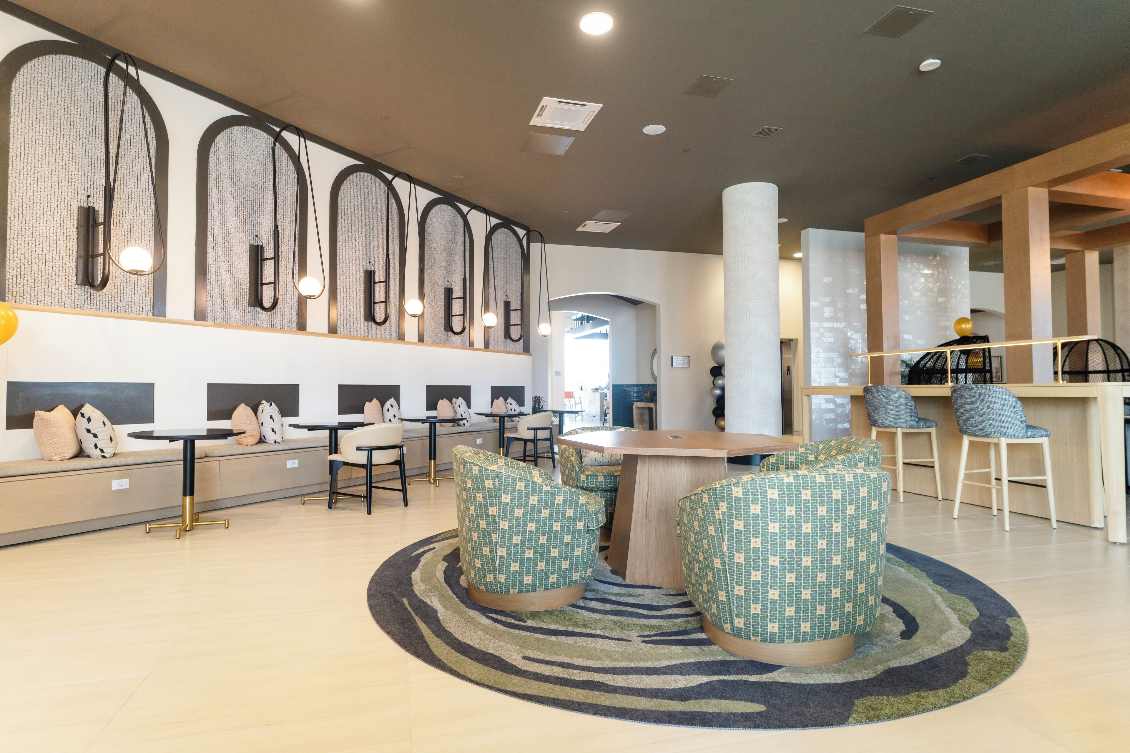 Ein moderner Lounge-Bereich mit Sitzgelegenheiten, einem zentralen Tisch und einer Bar.