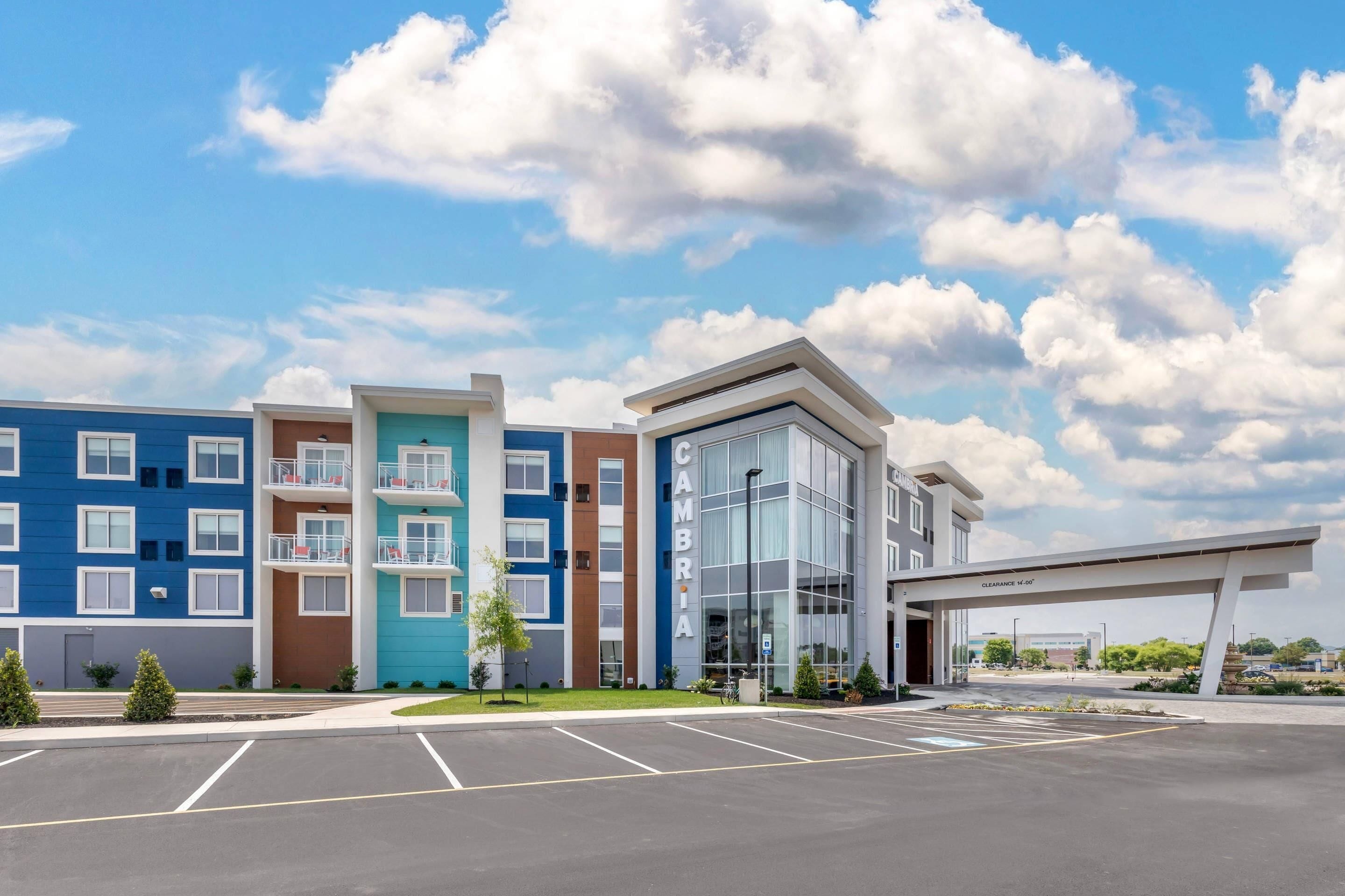 A multi-story hotel with a modern architectural design, featuring a parking lot in front.