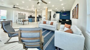 A spacious living area with a kitchen in the background, a ceiling fan, and a blue accent wall.