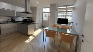 Una cocina moderna con comedor, suelo de madera y un amplio ventanal que proporciona luz natural.