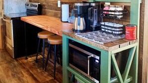 A rustic kitchen with wooden walls, a wooden countertop, a coffee machine, a kettle, and a microwave. - Briar Patch Cabin RRG: Firepit, Sunset, WIFI (Stanton)