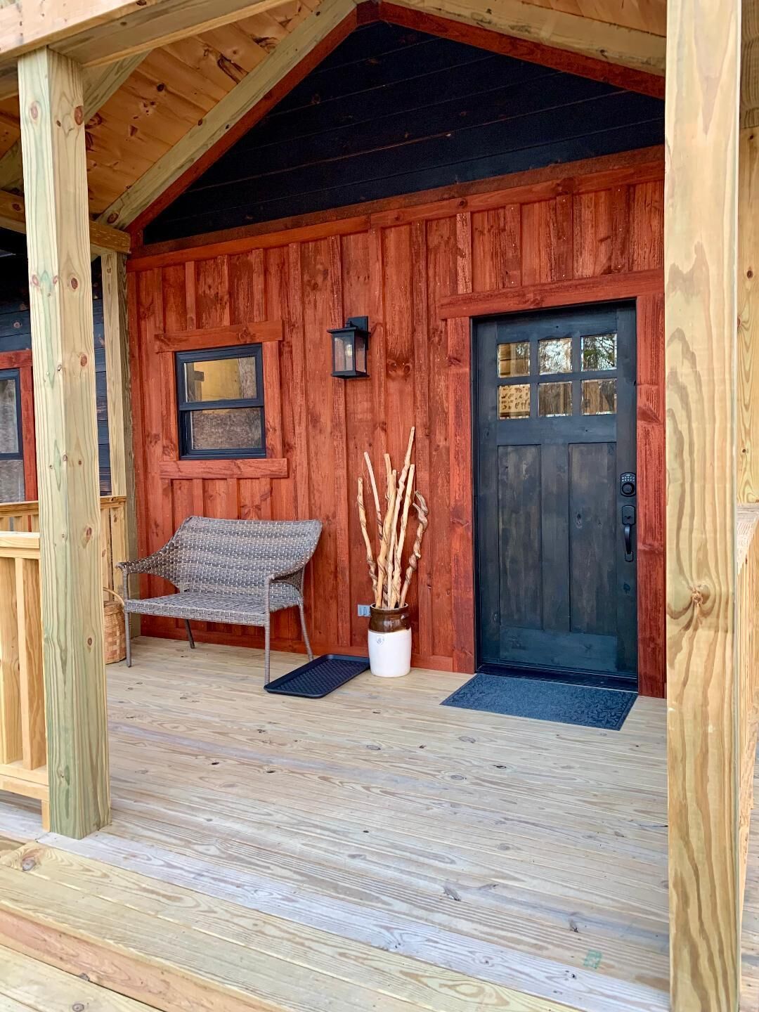 Une cabane en bois avec une véranda, un banc, une porte et une lanterne.