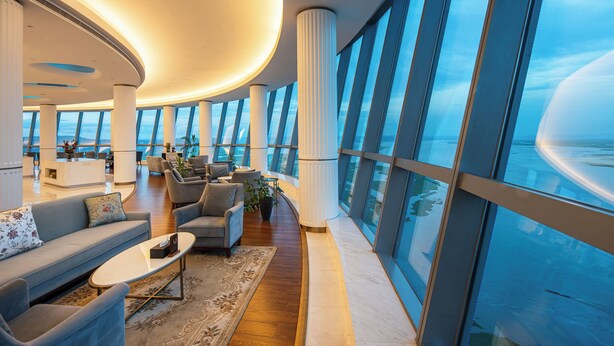 A spacious lobby with a curved ceiling, large windows, and a view of the ocean. - Hilton Brazzaville Les Tours Jumelles Hotel & Residences (Brazzaville)