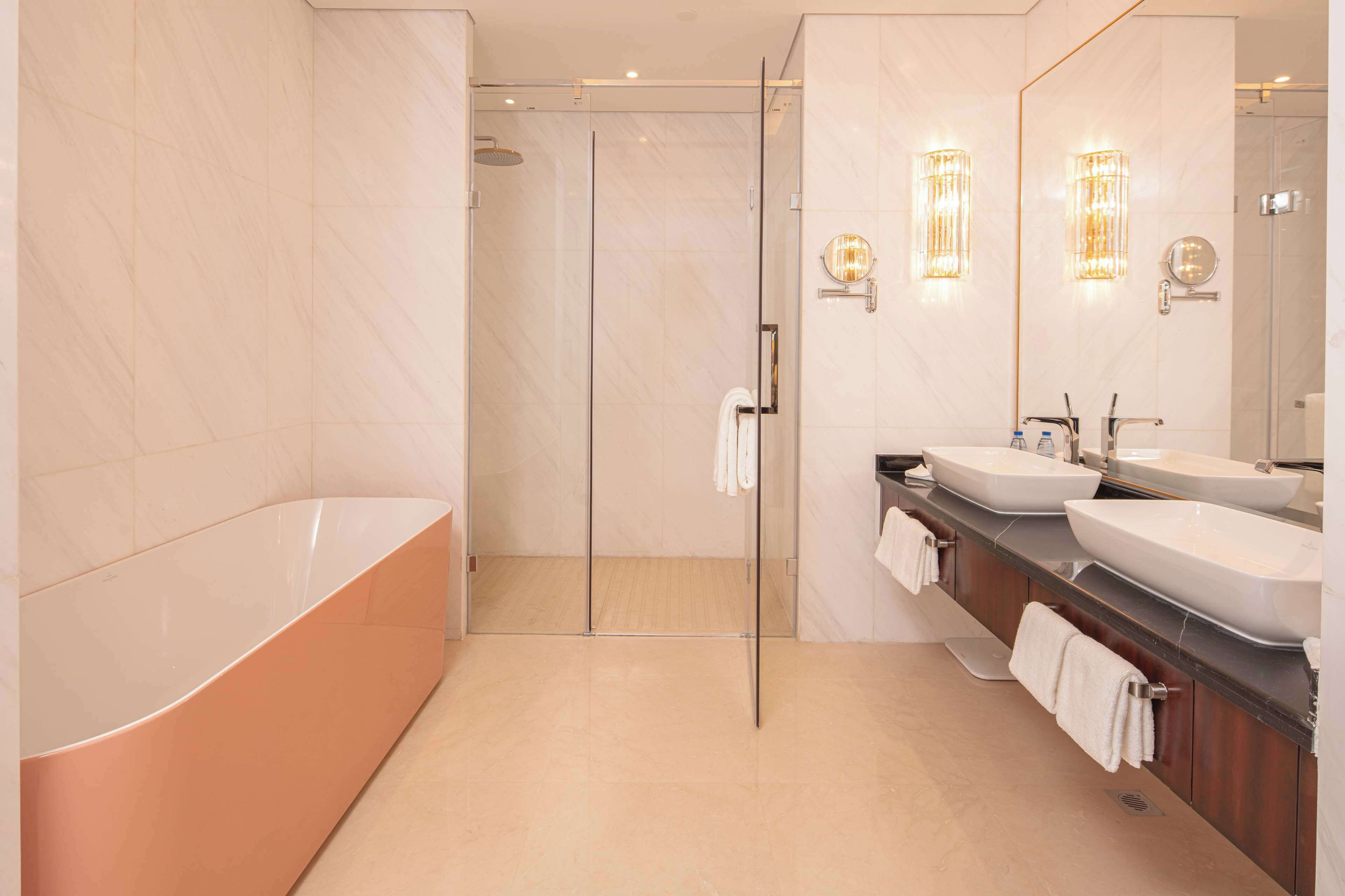 A modern bathroom with a glass-enclosed shower, a freestanding bathtub, and a vanity with two sinks.