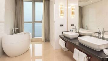 A modern bathroom with a freestanding bathtub, two sinks, and a large mirror.