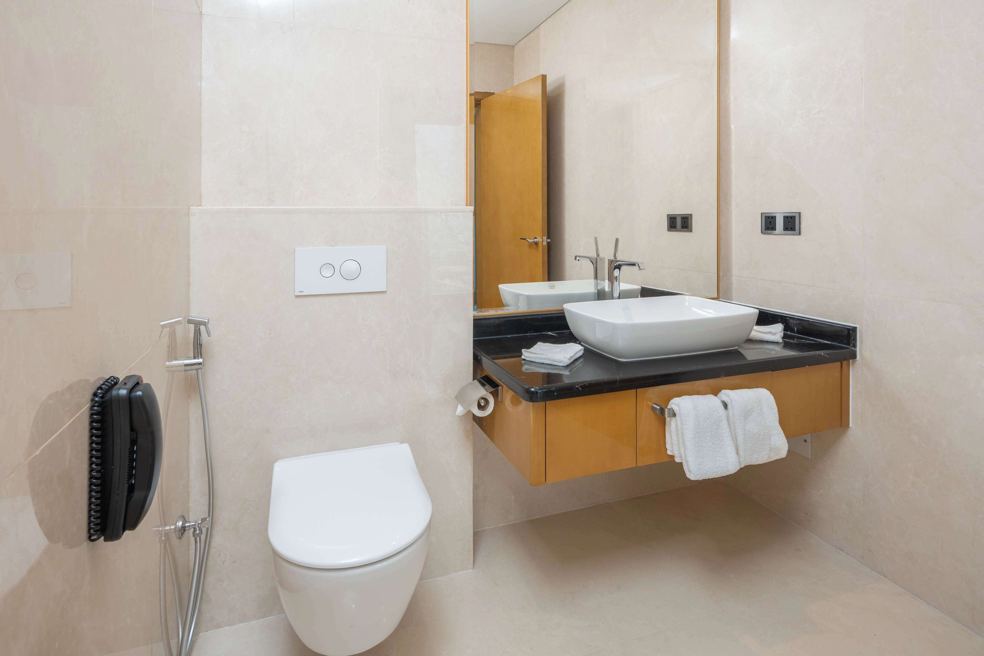 A modern bathroom with a toilet, a sink, a mirror, and a shower.