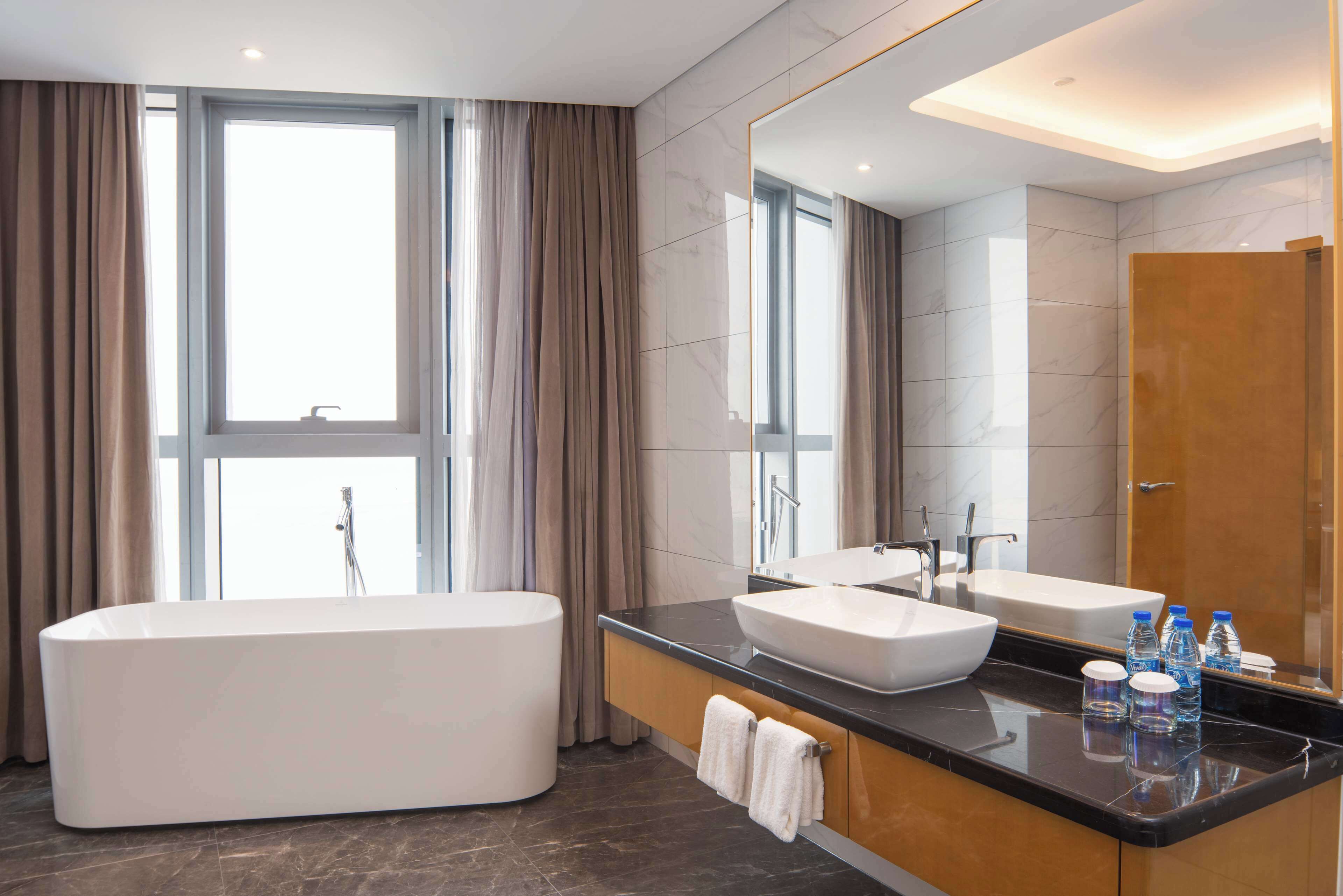 A modern bathroom with a freestanding bathtub, a vanity with a sink, and a large mirror.