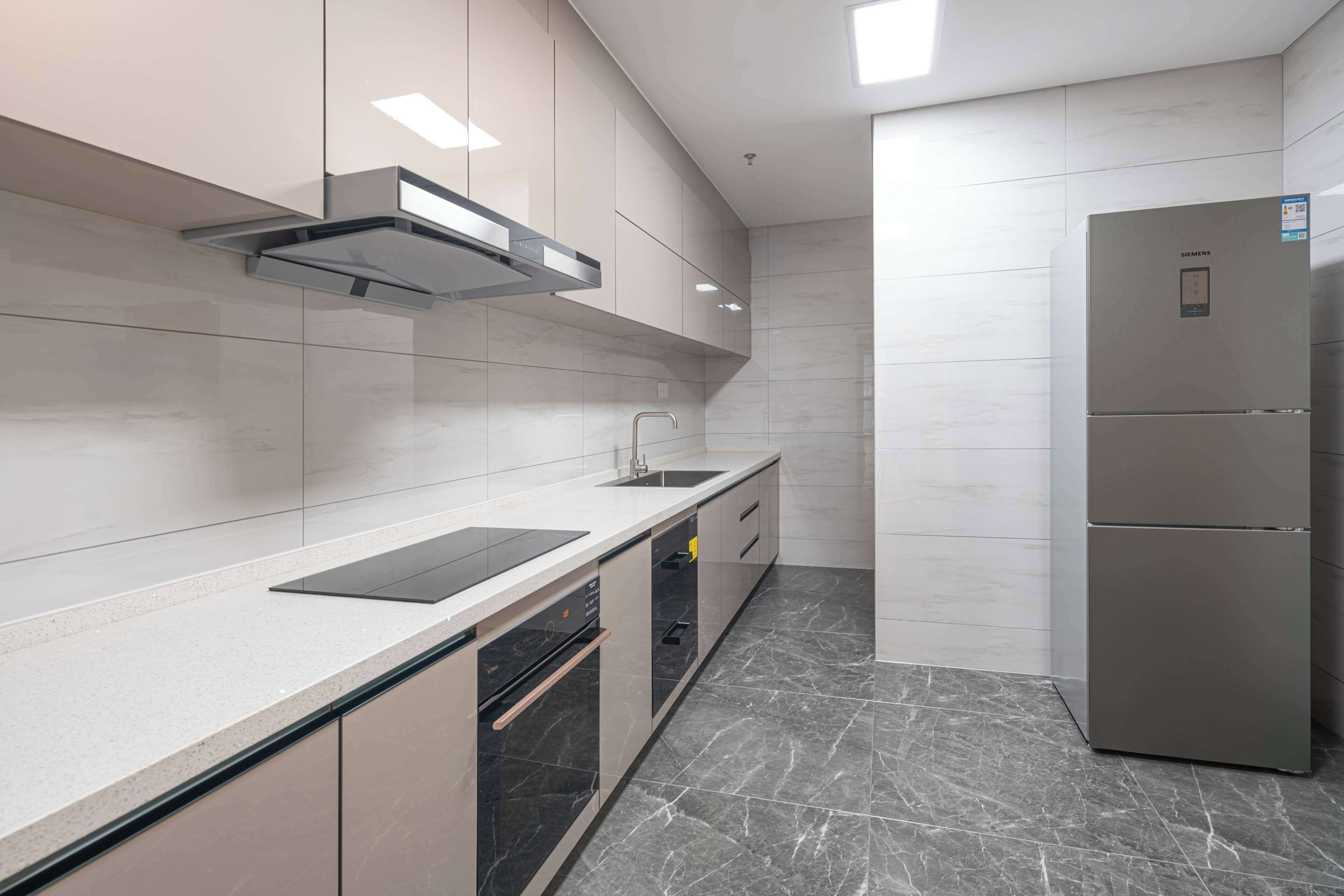 Una cocina moderna con un refrigerador de acero inoxidable, un horno empotrado y una encimera elegante.