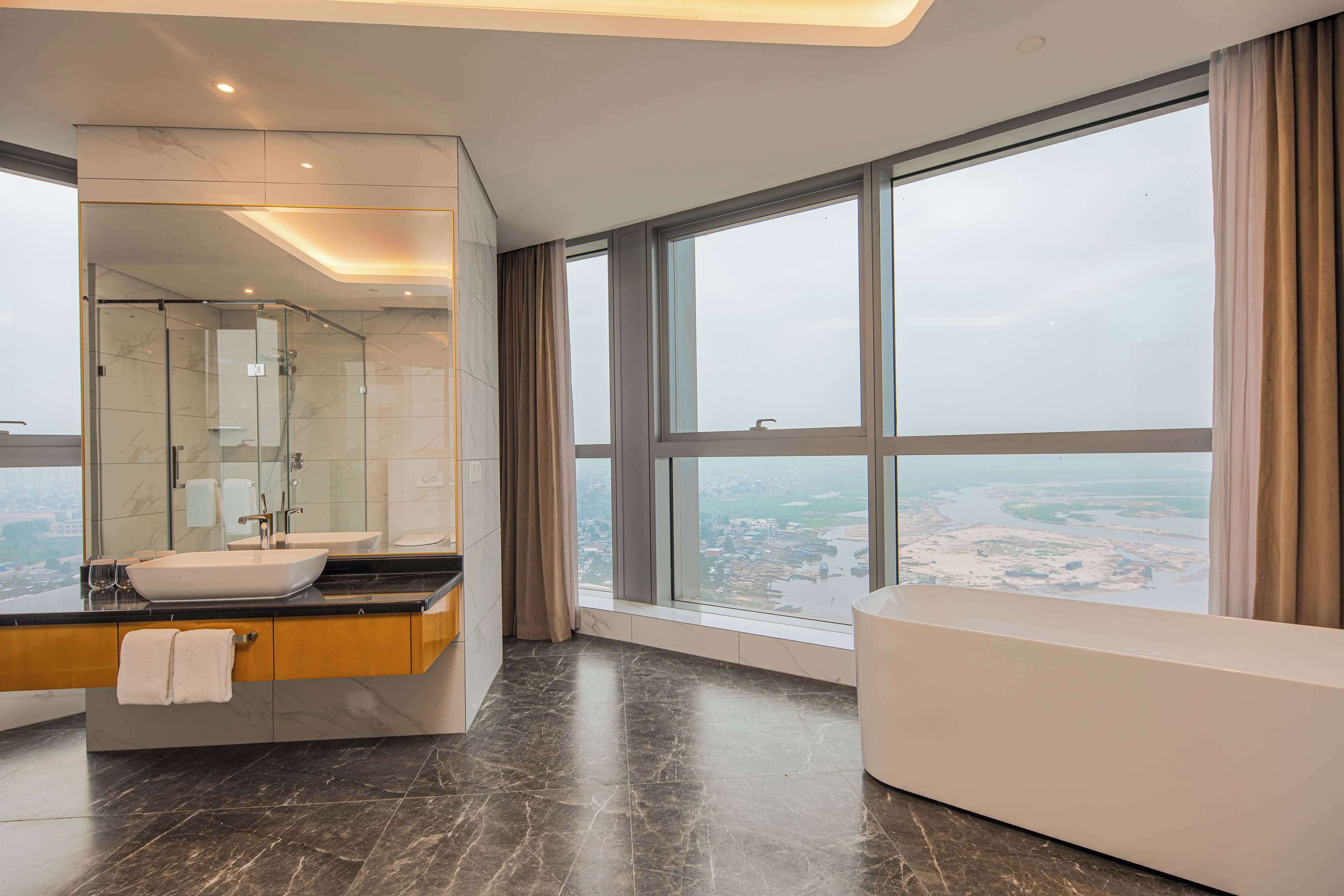 Un baño moderno con un espejo grande, un lavamanos y una bañera.
