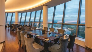 A spacious dining area with a panoramic view, large windows, and a modern interior design. - Hilton Brazzaville Les Tours Jumelles Hotel & Residences (Brazzaville)