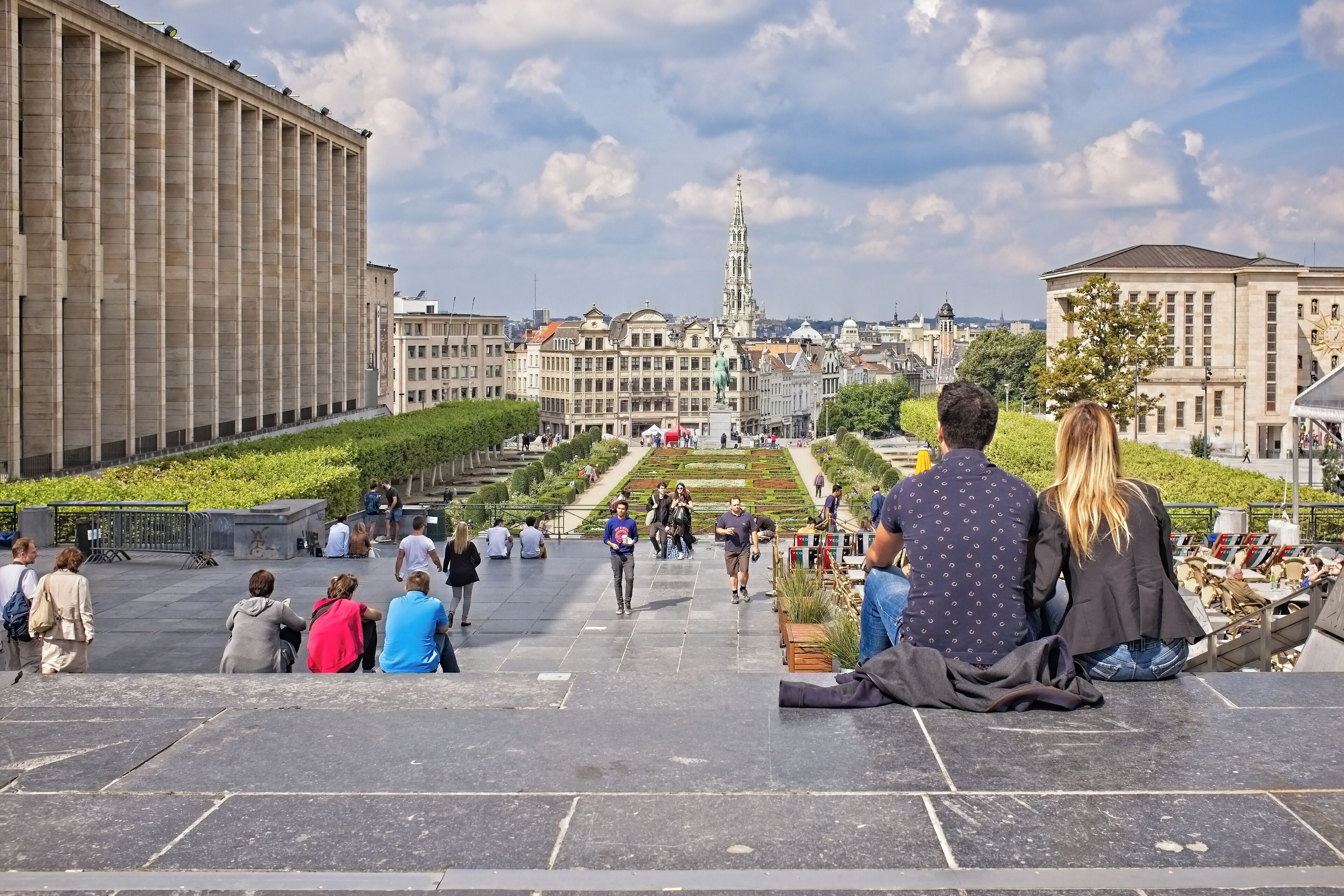 A public square with steps leading to a central area with a statue, surrounded by historic buildings.