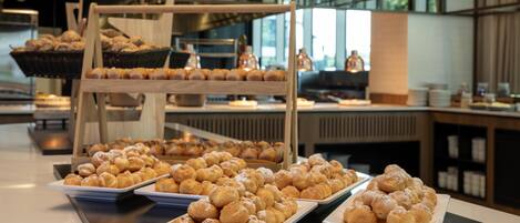 A buffet with various pastries and baked goods displayed on trays.