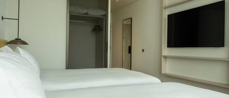 A hotel room with a bed, a wardrobe, a television, and a hanging light fixture.