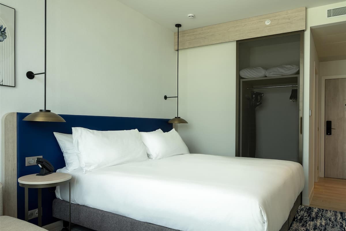 Ein Hotelzimmer mit Bett, Nachttisch, Lampe und Dusche.