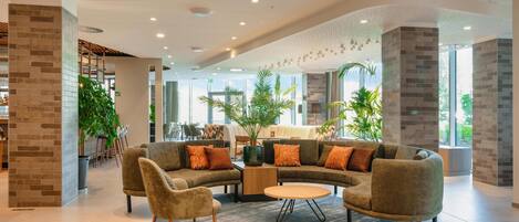 A modern lounge area with a curved sofa set, a small round table, and a potted plant.