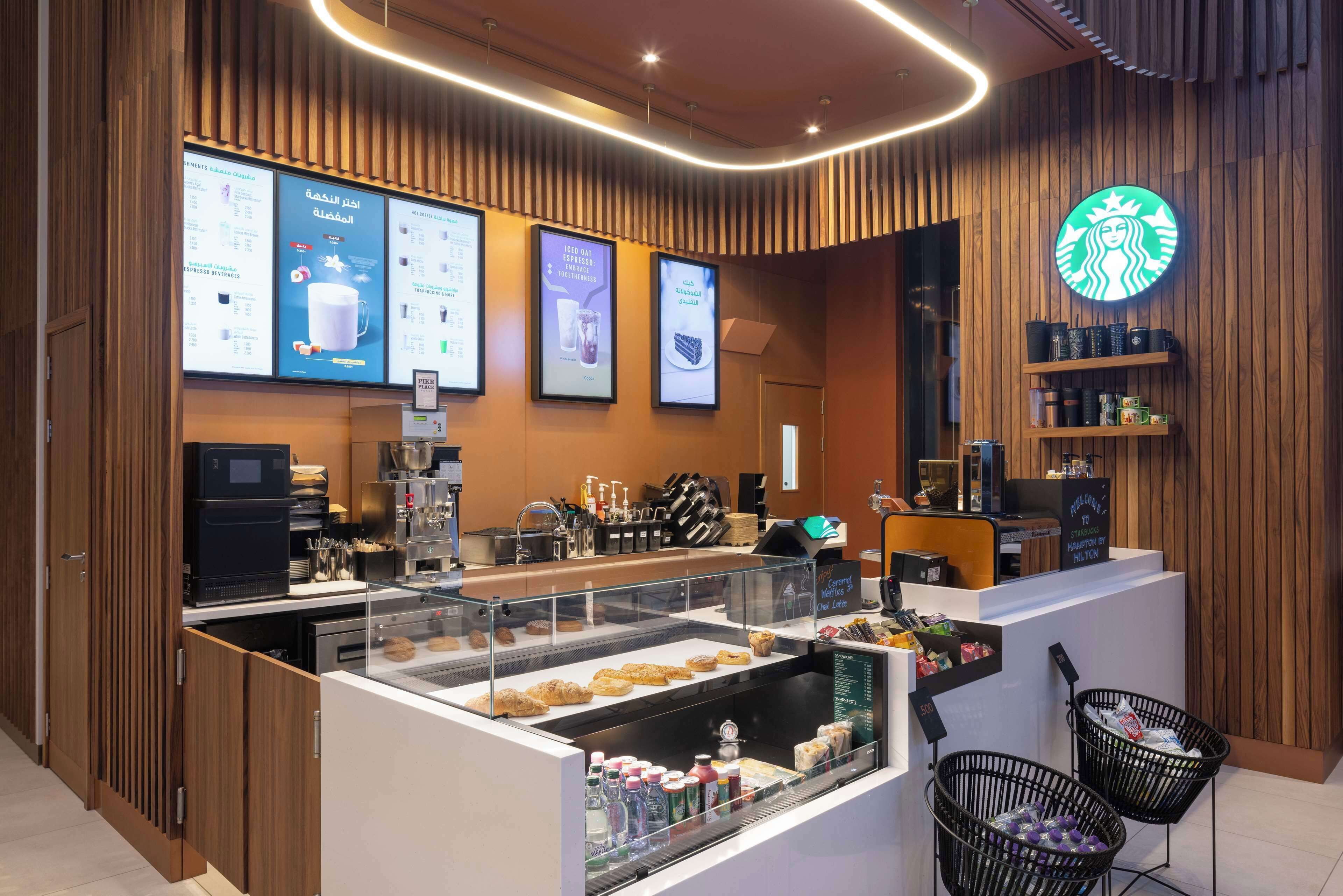 A modern coffee shop interior with a counter, menu boards, and a Starbucks logo.