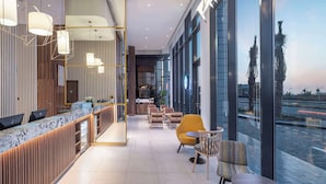 A modern hotel lobby with a reception desk, seating area, and large windows offering views of the cityscape. - Hampton By Hilton Kuwait Salmiya (Salmiya)