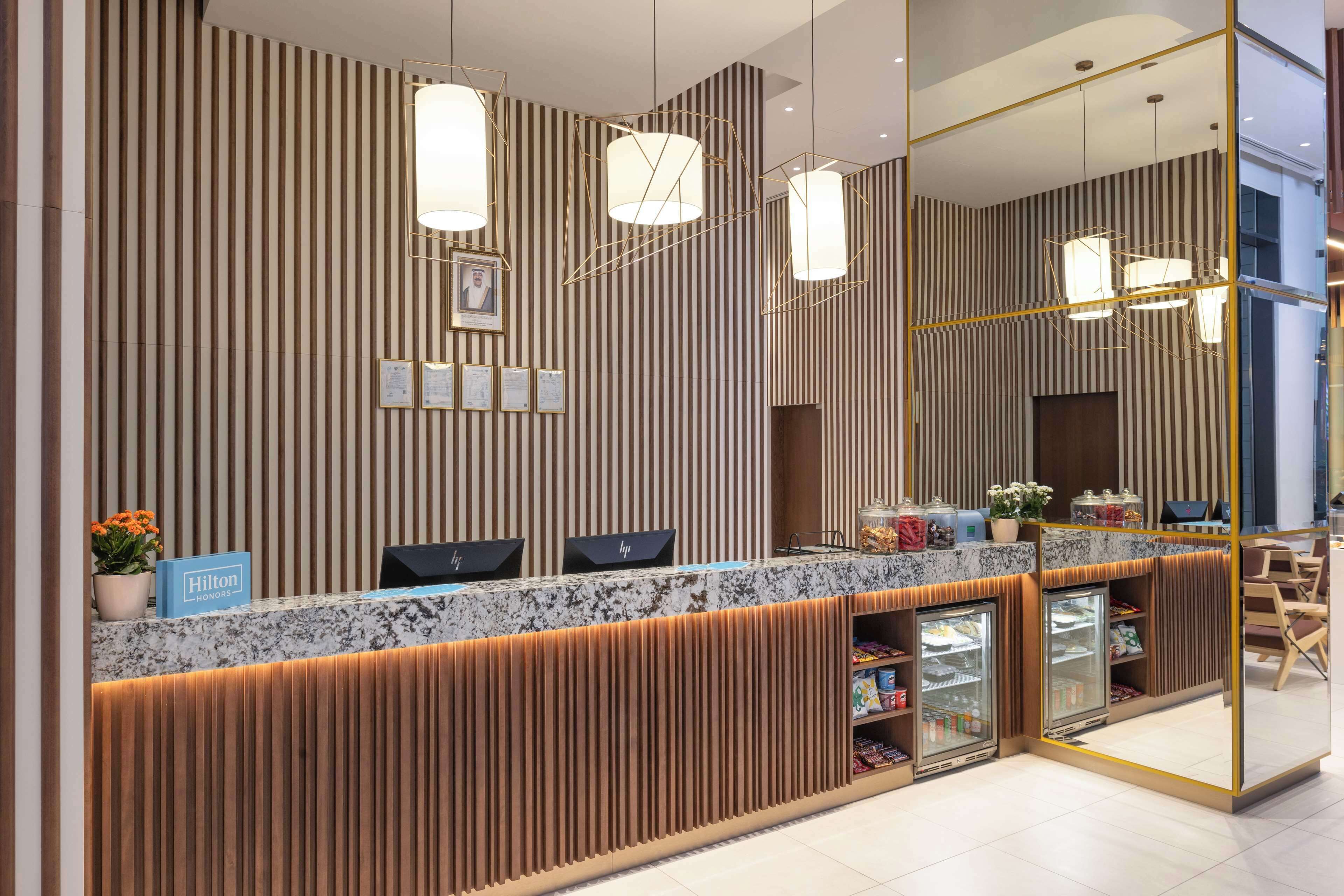 A hotel reception area with a striped wall, a marble counter, and a glass display case.