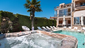 A hot tub with lounge chairs and a poolside area, surrounded by a hedge and a building with balconies. - Apartment Goran (Istria - Poreč) (Poreč)