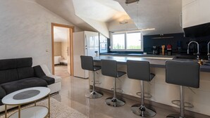 A modern kitchen with a central island, bar stools, and a dining area with a sofa and coffee table. - Apartment Goran (Istria - Poreč) (Poreč)