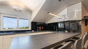 A modern kitchen with a large island, stainless steel appliances, and a view of the city. - Apartment Goran (Istria - Poreč) (Poreč)