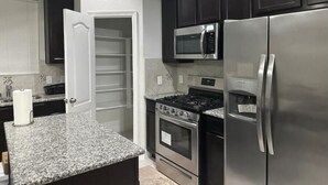 A kitchen with dark cabinets, a stainless steel refrigerator, a microwave, and an oven.