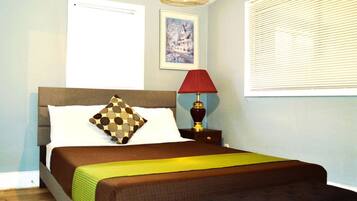 A neatly made bed with a patterned pillow, a bedside lamp, and a framed picture on the wall.