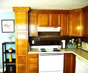 A kitchen with wooden cabinets, a white stove, and a countertop with various items.