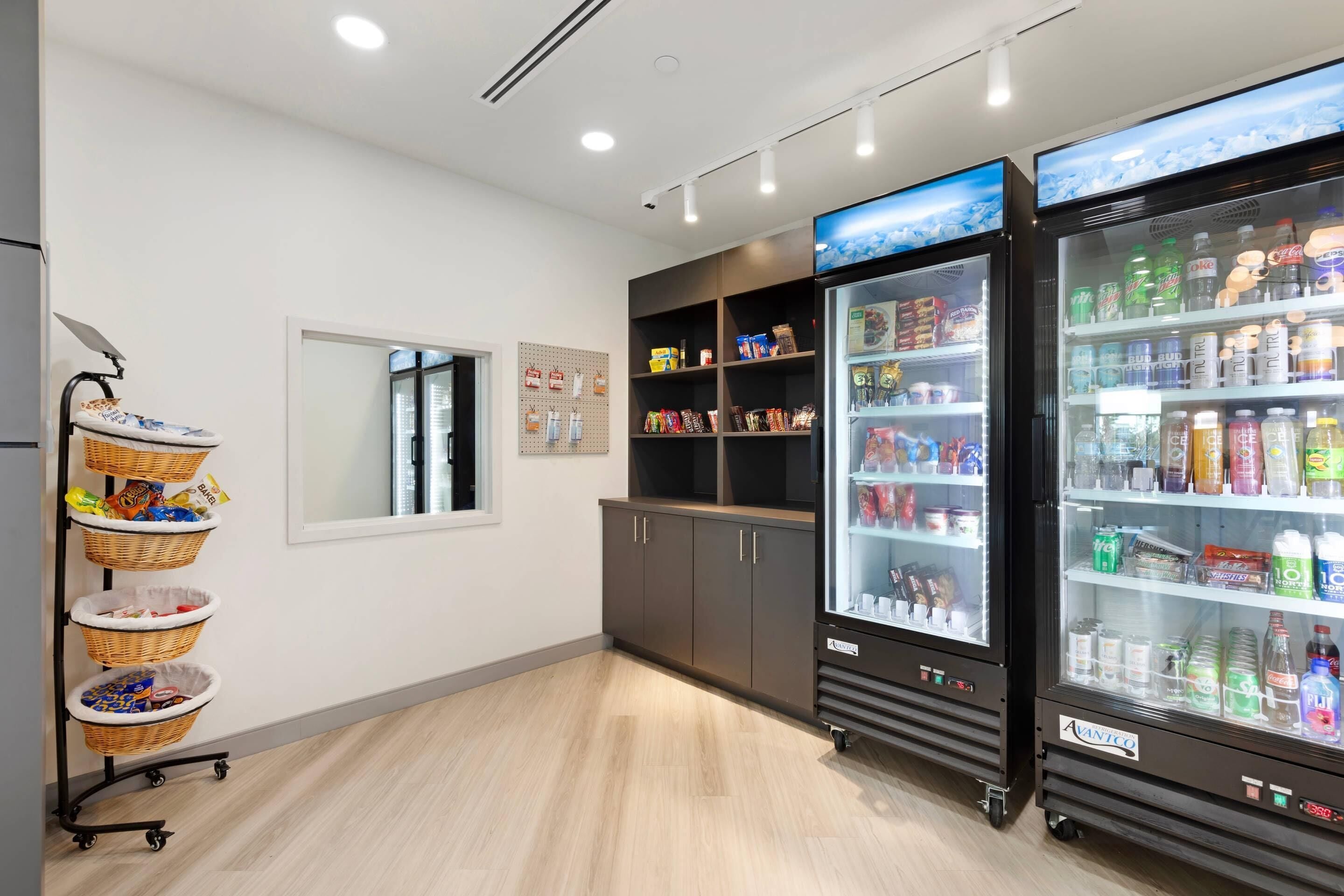 A clean, modern interior with two refrigerated beverage dispensers, a wicker basket cart, and a wall-mounted pegboard.