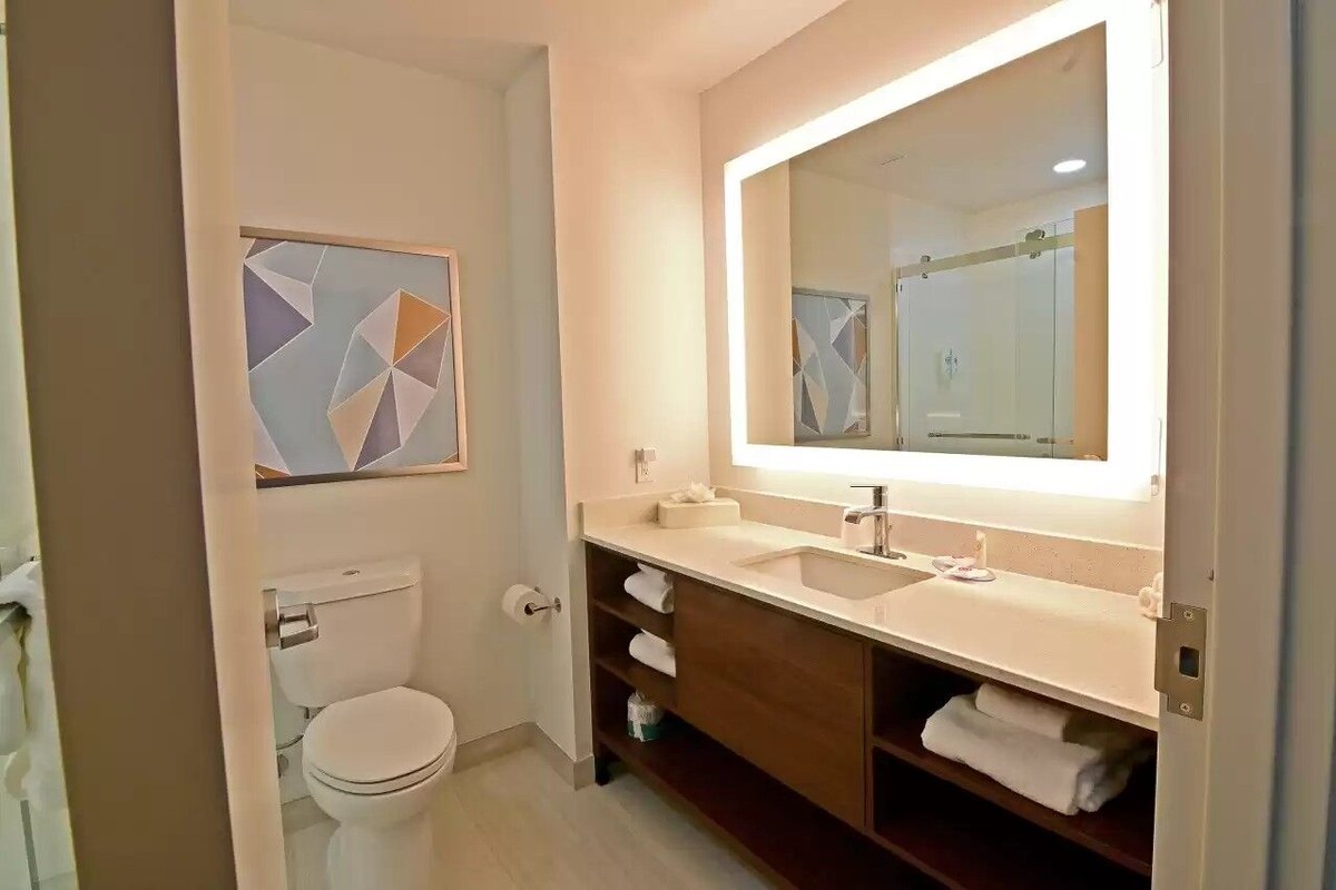 Ein modernes Badezimmer mit Toilette, Waschbecken, Spiegel und Handtuchhalter.