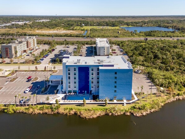 Un edificio moderno con fachada azul, estacionamiento y una masa de agua.